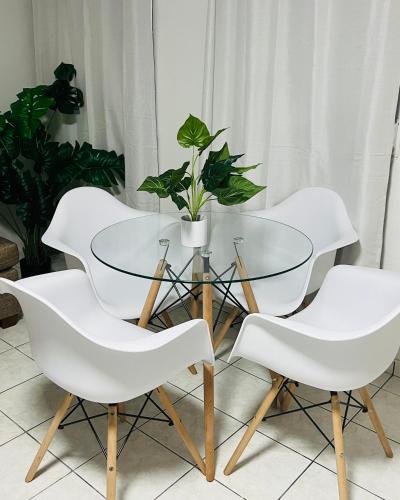 圣胡安San Juan apartments new的一张玻璃桌,上面有四把白色椅子和盆栽植物