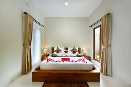 乌布Mahayoga Ubud Private Pool Villa And Spa的一间卧室,床上有红色的鲜花