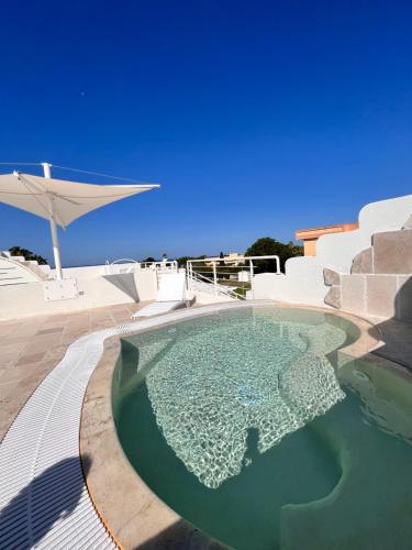 加利波利Residence Costa Bianca的一个带遮阳伞的游泳池和一个游泳池