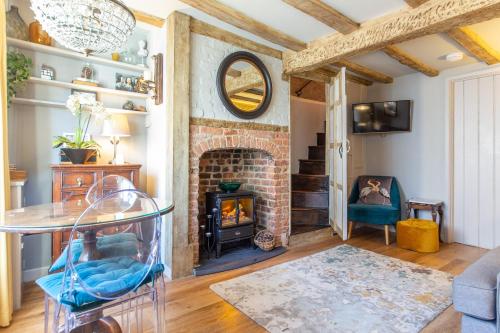 勒德洛Charlie's Cottage的客厅设有砖砌壁炉和桌子