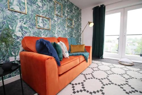 卡迪夫Vibrant 2 Br Apartment close to Cardiff Central的客厅里一张橙色的长沙发,墙上挂着