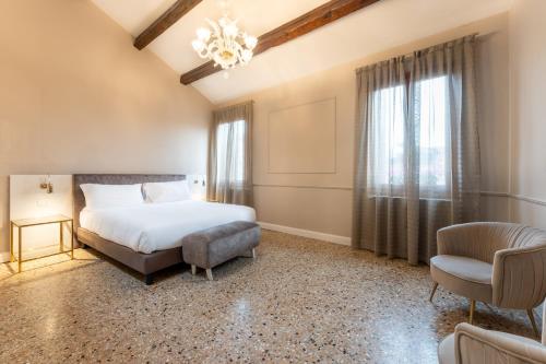 威尼斯San Vio Palace Luxury Apartments的一间卧室配有一张床、一把椅子和一个吊灯。