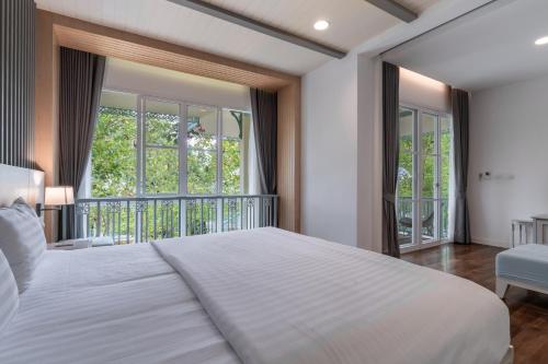 班奥南矛Na Sook Wellness Resort的一间带白色床的卧室和一个阳台