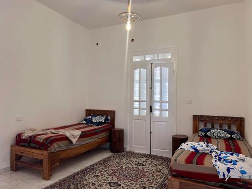 托泽尔Dar Zakaria Toursitic Area的一间卧室设有两张床,卧室内有一扇门