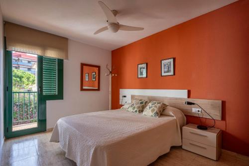 托里代巴拉AT044 Els Porxos的一间卧室设有橙色的墙壁和一张带风扇的床。