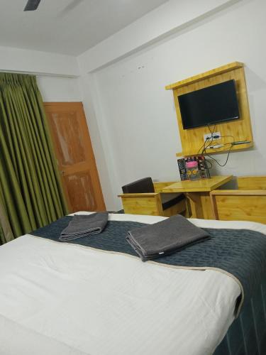 柴尔Hotel Grand View的一间卧室配有一张带书桌和电视的床。