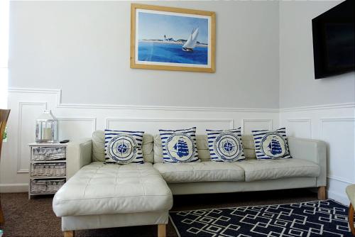 西卢港The Captain's Lodge Looe的客厅配有白色沙发,提供蓝色和白色枕头