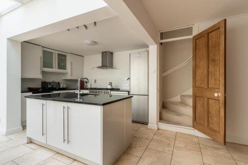 巴斯GuestReady - A Bohemian Home in Bath的厨房配有白色橱柜、水槽和门