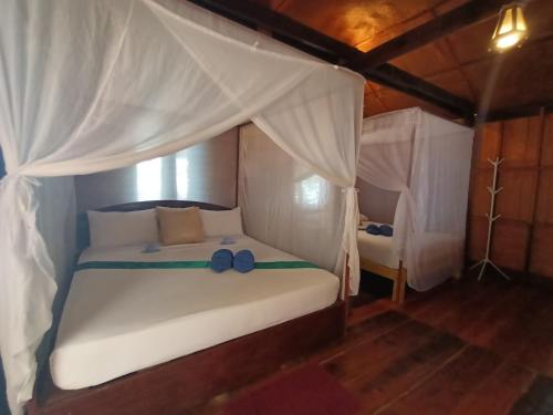 俊穆岛林山海简易别墅的一间卧室配有一张带天蓬的白色床