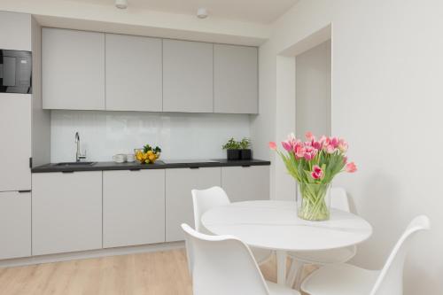 华沙Elegant & Cozy Apartment Pańska by Renters的厨房配有白色橱柜和白色花桌
