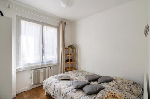 里昂Lyon Séjour Chambre Cozy pour une personne chez l habitant的卧室配有带枕头的床铺和窗户。