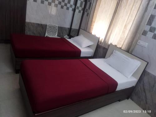 钦奈Surya's Guest House的配有红色和白色床单的客房内的两张床