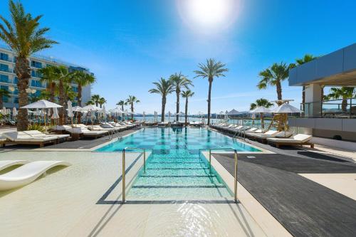 圣安东尼奥湾Amàre Beach Hotel Ibiza - Adults Recommended的一个带躺椅的游泳池,棕榈树