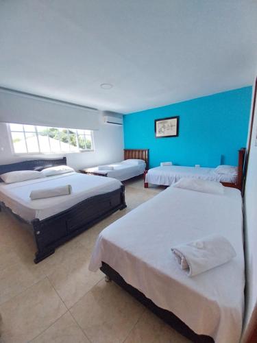 巴耶杜帕尔Hotel Sierra Nevada B&B SAS的一间设有三张床和蓝色墙壁的房间