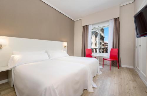 马德里Hotel Madrid Gran Via 25, Affiliated by Meliá的卧室配有一张白色大床和一张桌子及椅子