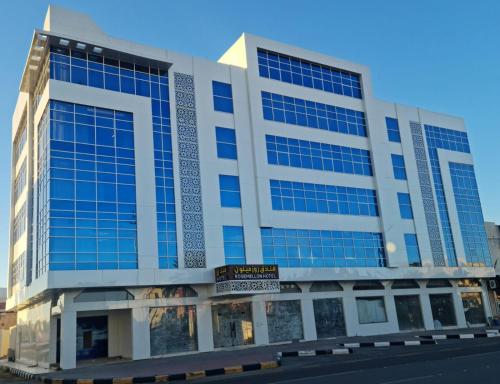 Al Fayşalīyahفندق روزميلون的街道上一座带蓝色窗户的大型建筑