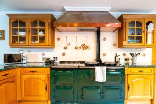 布里斯托Luxurious Country Retreat in Winford的厨房配有绿色橱柜和炉灶。 顶部烤箱