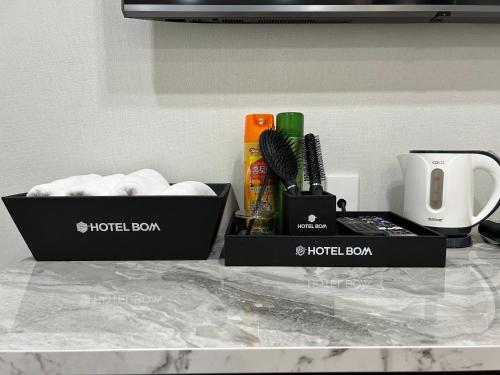 木浦市Hotel Bom的两个箱子,放在带毛巾的柜台上
