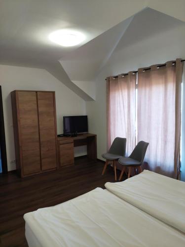 珀尔蒂尼什Pensiunea Grandor的一间卧室配有两把椅子、一张床和电视