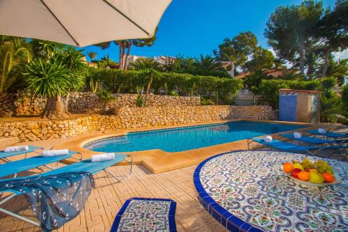 拉坎努塔Villa Sanlio - PlusHolidays的一个带椅子和遮阳伞的游泳池以及一碗水果