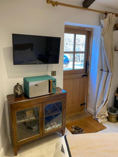 CowdenPriory Cottage Stables的客厅设有壁挂式电视和桌子。