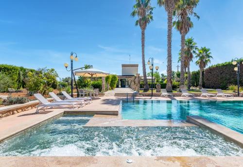 丽都玛里尼Masseria Tenuta Specolizzi的一个带躺椅的游泳池,棕榈树