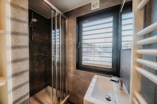 佩讷明德Hausboot Trinity - LP5的带淋浴和盥洗盆的浴室以及窗户。