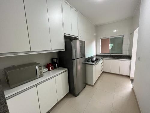 卡皮托利乌Apartamento Aconchegante的厨房配有白色橱柜和不锈钢冰箱