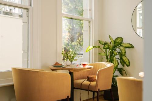 伦敦Sonder Kensington Gardens的一间带桌椅和窗户的用餐室