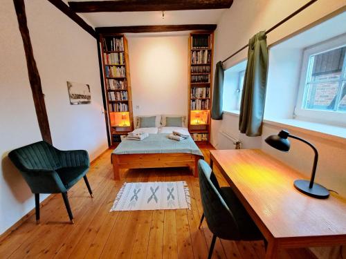 SuderburgFerienwohnung im Heidjerhaus的客房设有一张床、一张桌子和一把椅子。