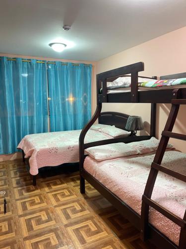 萨利纳斯Hostal Costa Linda Salinas的配有蓝色窗帘的客房内的两张双层床
