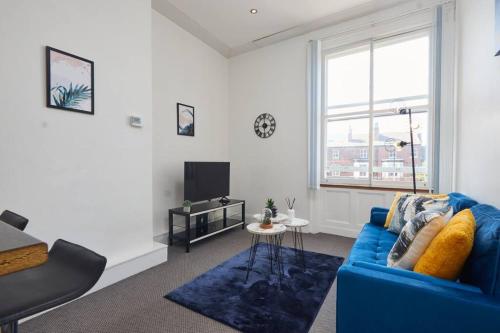 利兹Stylish 2 Bed Apt in Leeds Centre - FREE Parking! Contact us for Better Offers!的客厅配有蓝色的沙发和电视