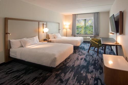 纳什维尔Fairfield Inn & Suites by Marriott Nashville Airport的酒店客房配有两张床和一张书桌