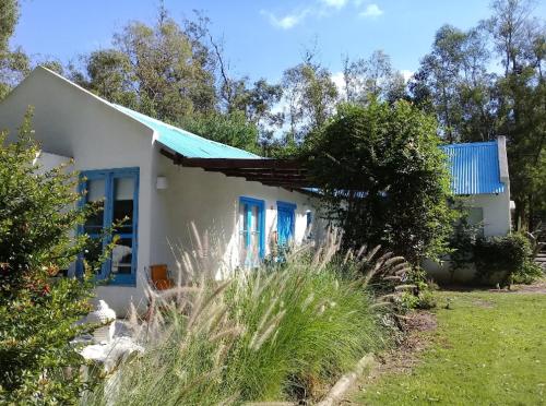 巴拉德马尔多纳多Habitación payesa en el bosque, La Barra的一间白色的小房子,有蓝色的窗户和草地