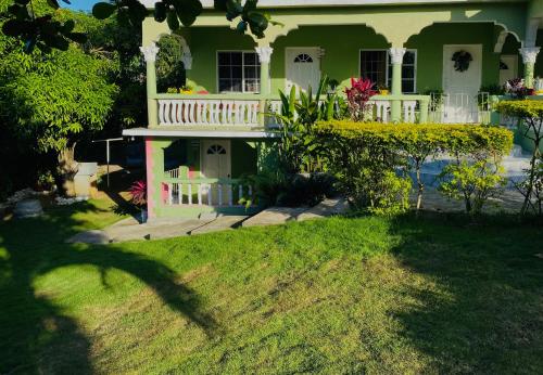 欧丘里欧Cindy's Garden Stay的庭院内带白色阳台的绿色房屋