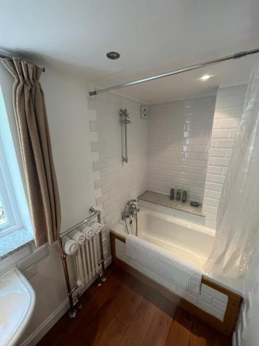 卡斯尔顿Torside Holiday Cottage的白色的浴室设有浴缸和水槽。