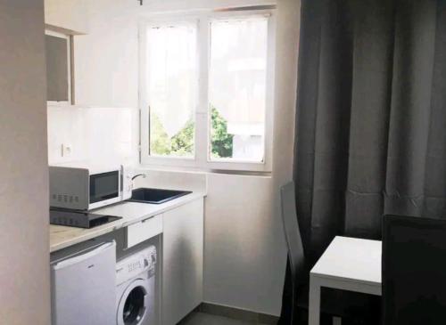 让蒂伊Appartement Charme petite terrasse à 400m de Paris的厨房配有洗衣机和窗户。