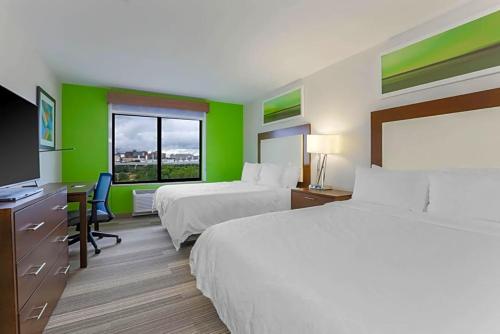 沃思堡Holiday Inn Express & Suites Downtown的酒店客房设有两张床、一张桌子和一台电视。
