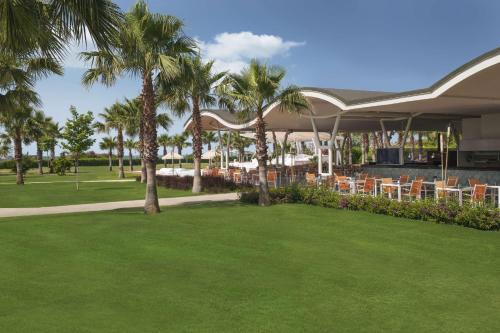 达拉曼达拉曼萨里格尔梅希尔顿spa度假酒店 的公园里一家餐厅,餐厅里摆放着椅子和棕榈树