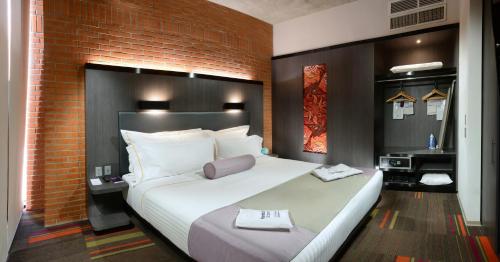 瓜达拉哈拉Hotel Guadalajara Country Club by HNF的砖墙房间内一张大白色的床