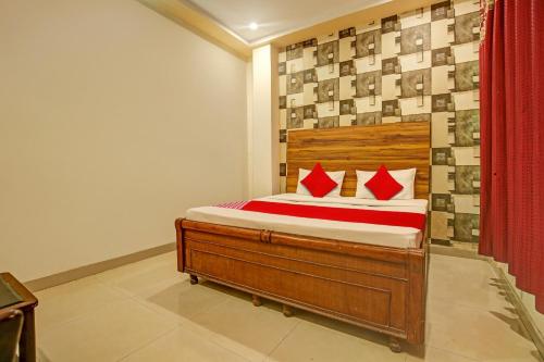 BanūrSuper OYO Hotel NR Residency的一间卧室配有一张带红色枕头的木床。