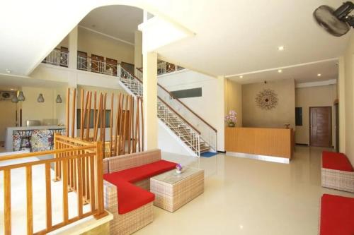 库塔Kuta Suci Guesthouse的一间带楼梯和红色长凳的客厅