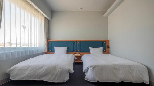 土浦市Hotel Global View Tsuchiura的两张睡床彼此相邻,位于一个房间里
