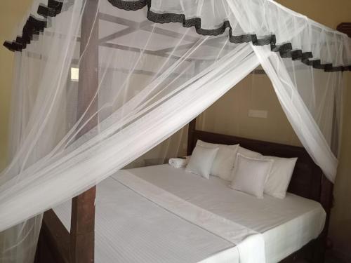 坦加拉Appu Villa的卧室配有带白色窗帘的天蓬床