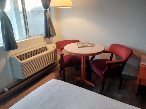 布鲁金斯Harbor Inn的客房设有桌子、两把椅子和窗户。