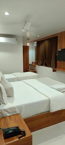 甘地讷格尔Hotel Royal Relax的一间设有三张床的房间和一张桌子上的电话
