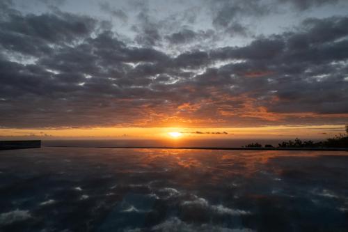 珀蒂蒂勒Villa Mahot的日落在水体上,日落在太阳下