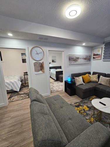 勒杜克Beautiful 2 Bedroom Guest Suite in Leduc 11 mins to Edmonton Intl Airport, Free Wifi, Netflix ,Cable & Workstation的客厅配有沙发和墙上的时钟