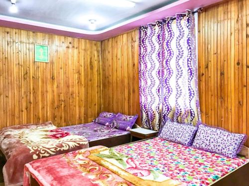 SombāriBODHI VILLA的配有木墙和窗帘的客房内的两张床