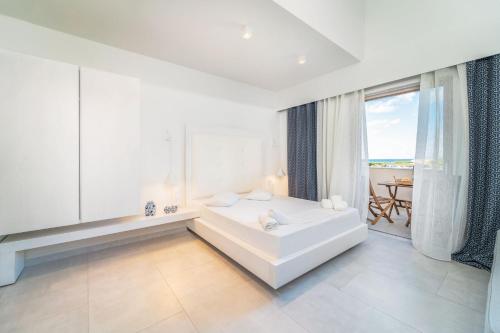 雷夫卡达镇San Giovanni Beach Resort and Suites的一间白色卧室,配有浴缸和大窗户
